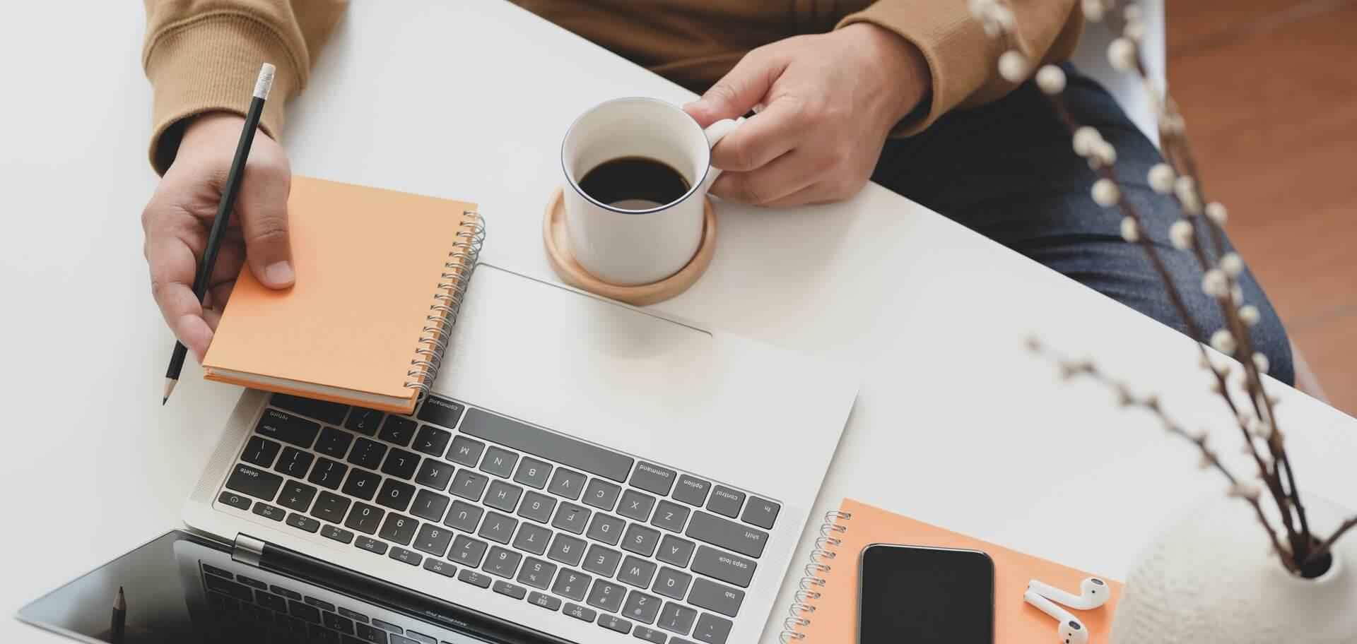 Laptop, phone, earphone and notepads on a desk